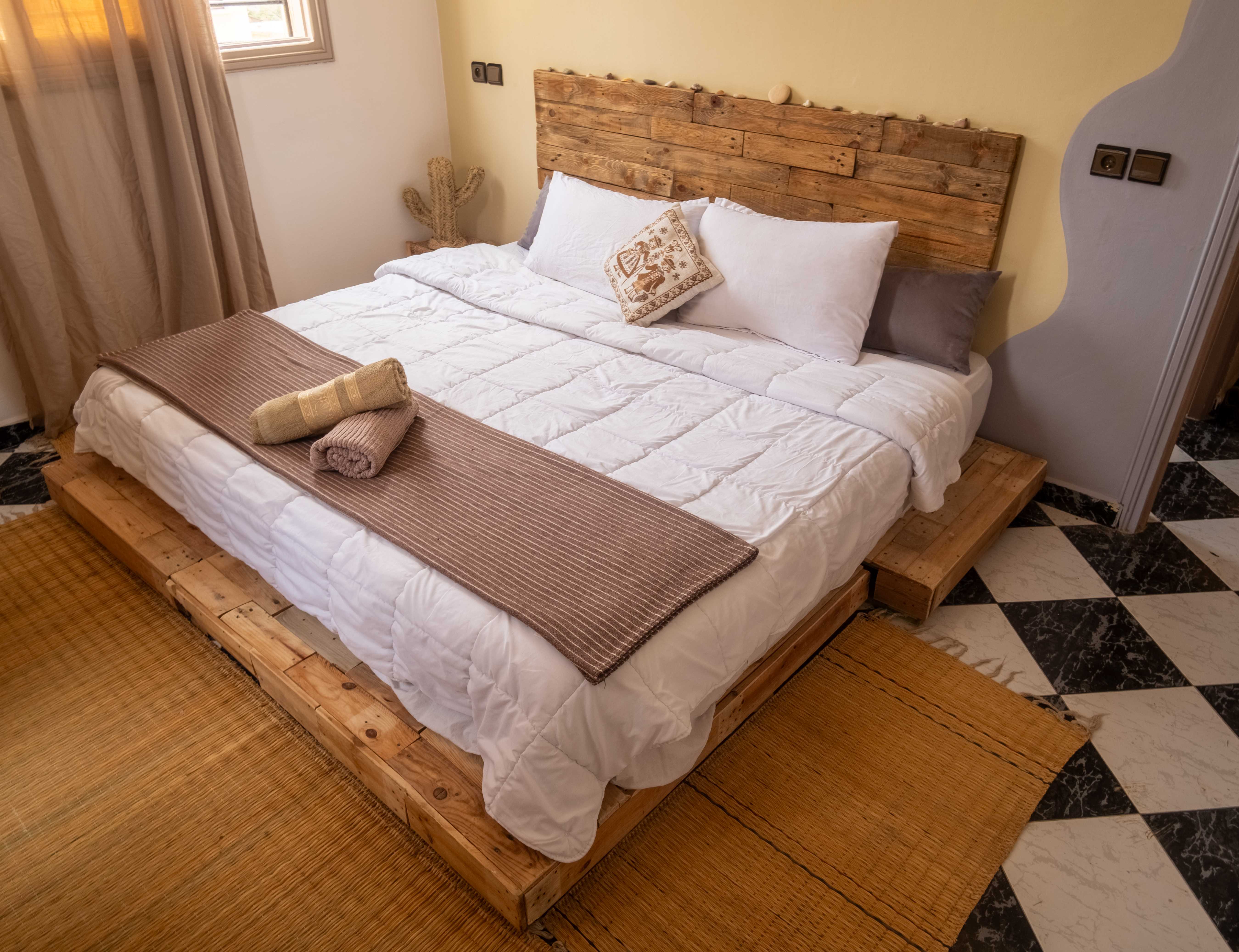 Rustic bedroom with wooden pallet bed and checkered marble flooring